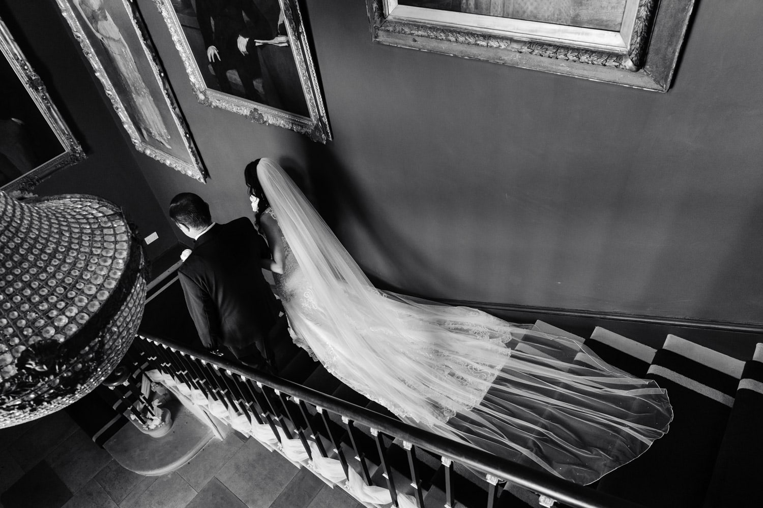 bride walks down the stairs at Stubton Hall with her dad. Black & white Editorial style wedding photo by Nottingham wedding photographer Martin Cheung